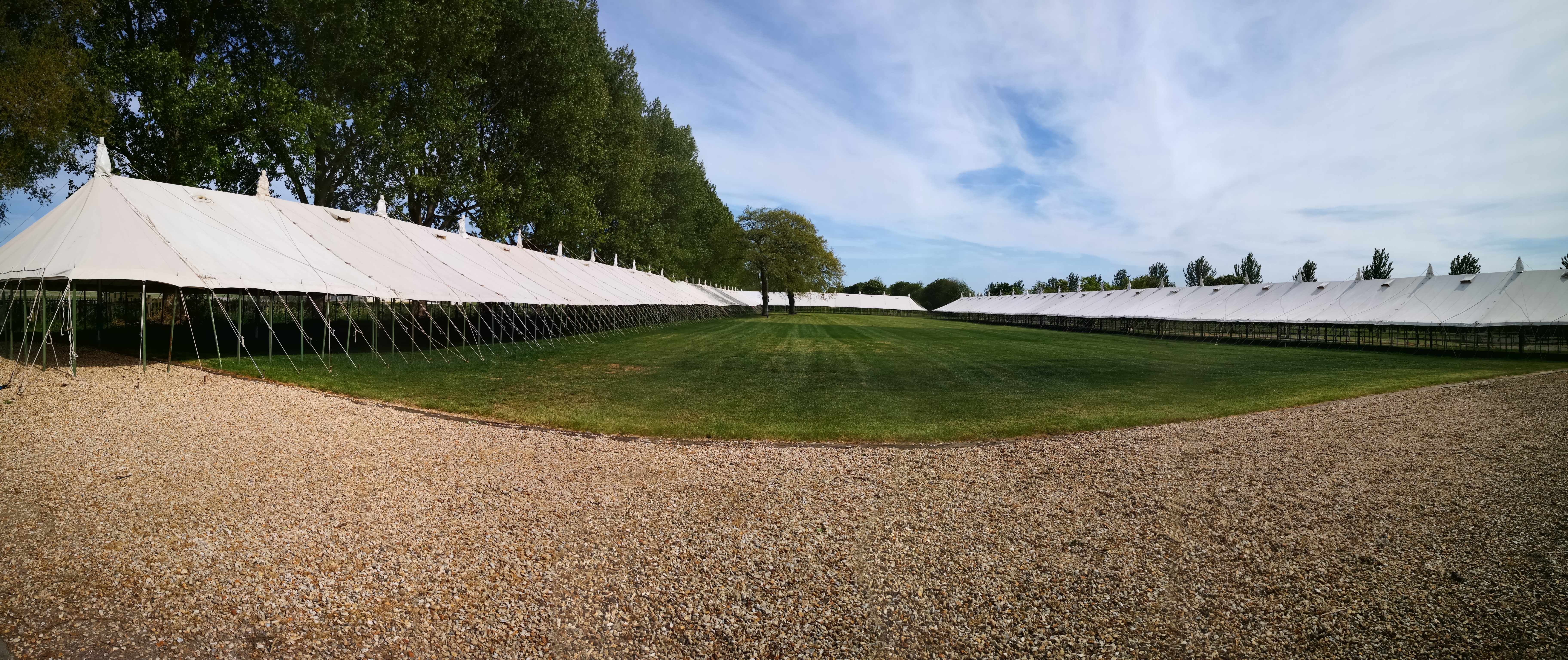 A graveled pathway at Bath & West Showground with large open sided traditional marquees surrounding the path and grass. 
