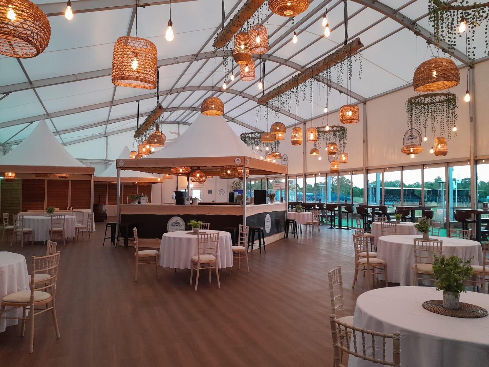 interior shot of the Danco marquee hospitality tent at Badminton Horse Trials 2025. A wooden floor, range of tables and chairs and a bar inside a coned tent.  