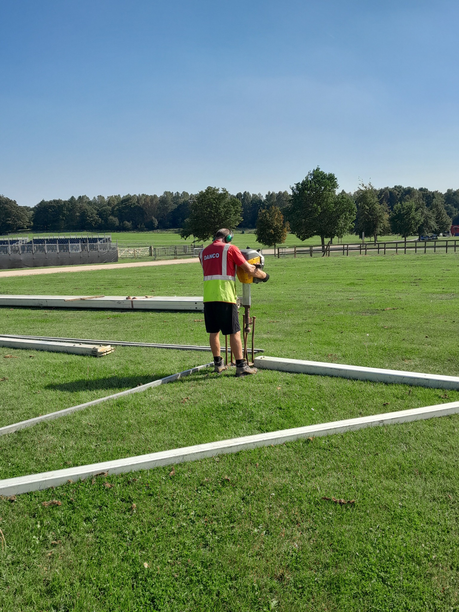 Danco employee in hi-vis and wearing ear defenders erecting a marquee. 